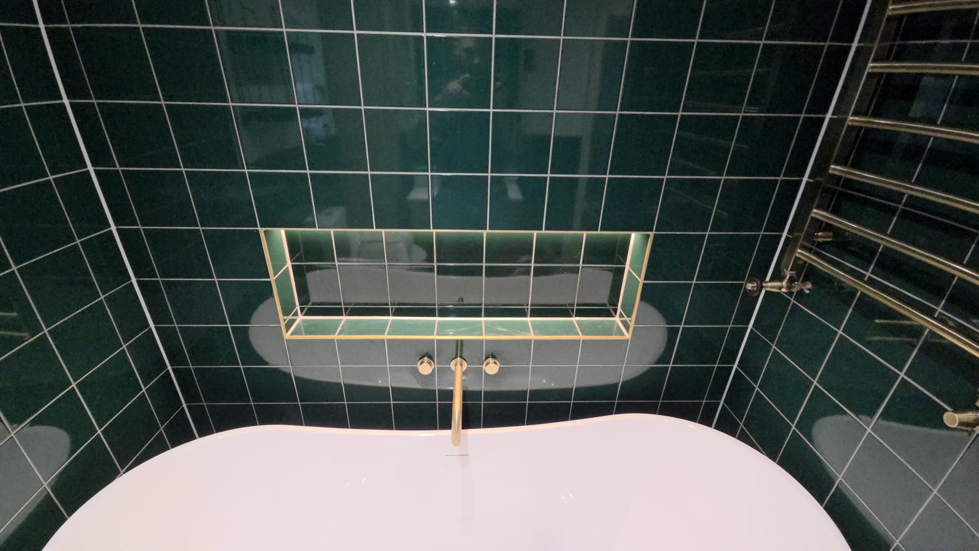 Detail of teal tile installation with brass fixtures